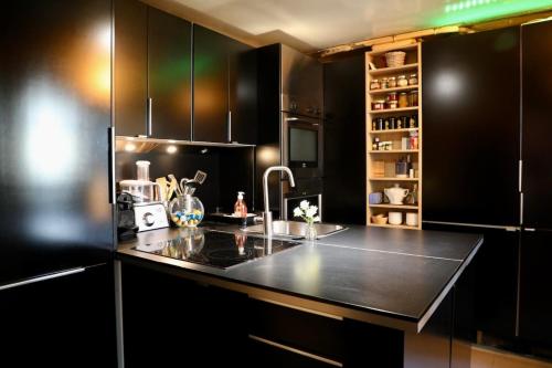 - une cuisine avec des placards noirs et un évier dans l'établissement Appartement 74m2 in the center of Paris, à Paris