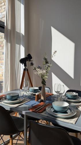 a dining room table with plates and glasses on it at Tranquil & Bright by The Canal in London