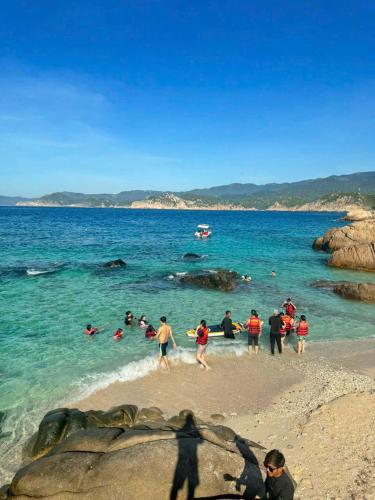 a group of people playing in the water at the beach at Hồng Tranquil Homestay Vĩnh Hy in Ninh Hải