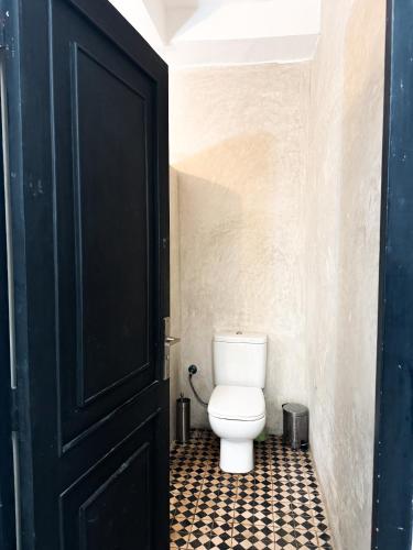 a bathroom with a toilet and a black door at sunset taghazout in Taghazout