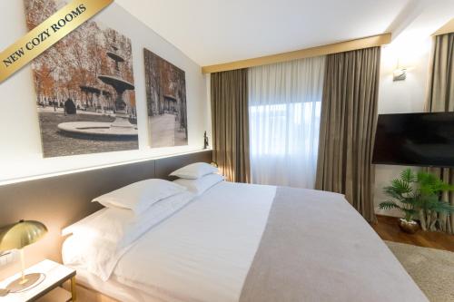 a bedroom with a large white bed and a large window at Hotel Jarun in Zagreb
