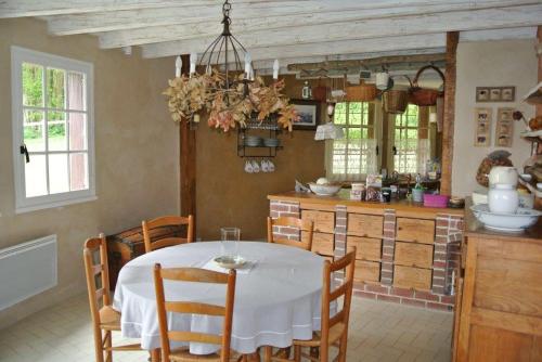 une cuisine et une salle à manger avec une table et des chaises blanches dans l'établissement Chaumière de charme, à Morisel