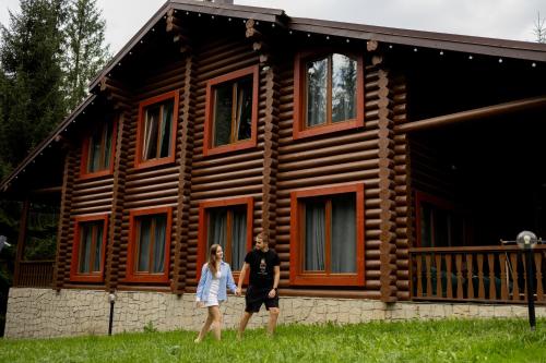 a man and a woman standing in front of a log cabin at Маєток Ліс і Гори in Bukovel