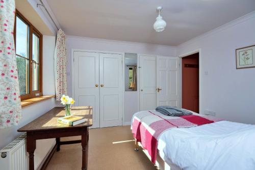 a bedroom with a bed and a table with a vase on it at Finest Retreats - Cwmfron House in Llanidloes