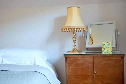 a lamp on a dresser with a mirror and a bed at Finest Retreats - Cwmfron House in Llanidloes
