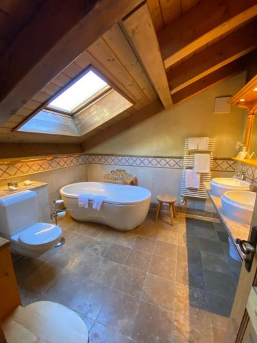 a bathroom with two sinks and a tub and two toilets at Hotel Berghof in Zermatt