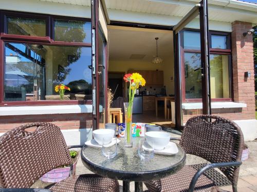 a table with two chairs and a table with flowers on it at Hazelwood Holiday Home in Sligo