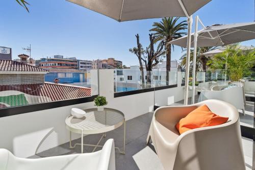 a balcony with a table and chairs and an umbrella at Las Dunas de Santa Catalina Boutique House in Las Palmas de Gran Canaria