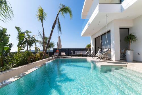 a swimming pool in front of a house with palm trees at Blue Hills Villa in Kallithea Rhodes