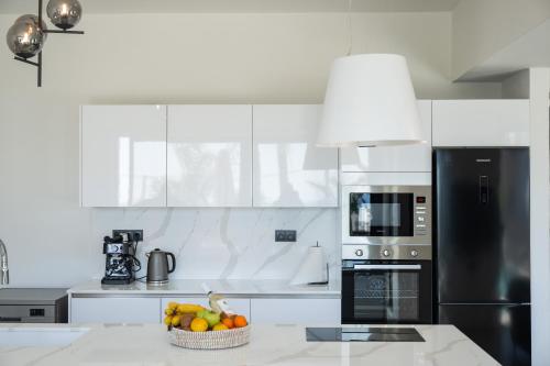 a white kitchen with a bowl of fruit on a counter at Blue Hills Villa in Kallithea Rhodes
