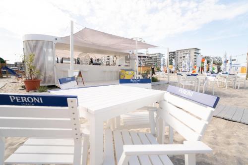 a white picnic table and two chairs on the beach at Nayino Resort Hotel in Mamaia Nord