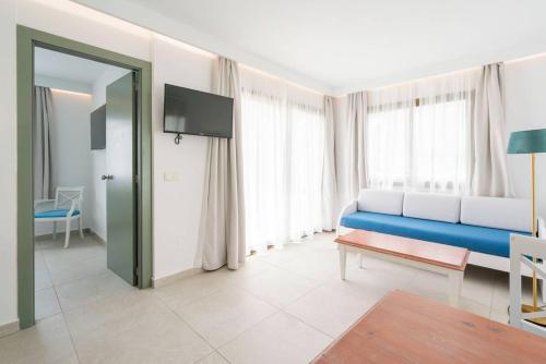 a living room with a blue couch in front of windows at Guya Wave Hotel in Cala Ratjada