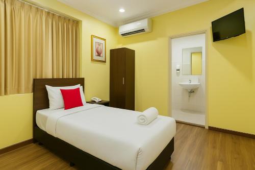 a bedroom with a bed with a red pillow and a sink at Hotel Sunjoy9 Bandar Sunway in Petaling Jaya
