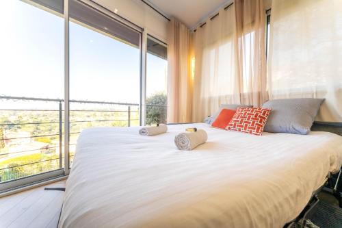 - une chambre avec un grand lit blanc et de grandes fenêtres dans l'établissement Magnifique appartement avec piscine et jardin, à Nice