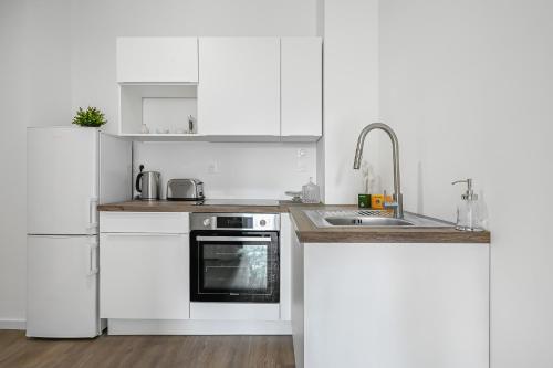 La cuisine blanche est équipée d'un évier et d'un réfrigérateur. dans l'établissement Le CityNest - 4 pers - Parking - Wifi, à Évreux