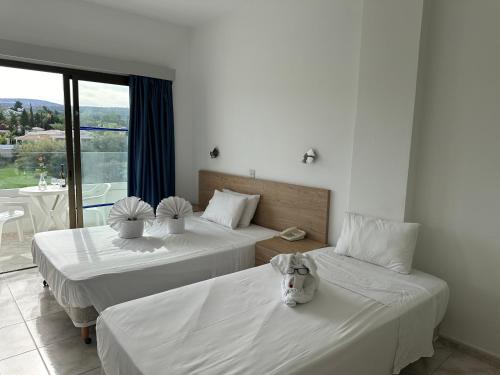 two beds in a room with a large window at Souli Beach Hotel in Polis Chrysochous