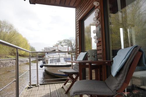 a balcony with two chairs and a table and a boat at Hausboot Stöckte in Winsen Luhe
