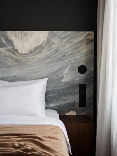 a bedroom with a bed with a painting on the wall at Hotel Reja, a Member of Design Hotels in Klaipėda