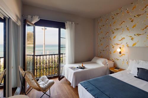a bedroom with two beds and a balcony with the ocean at Hotel Ribadesella Playa in Ribadesella