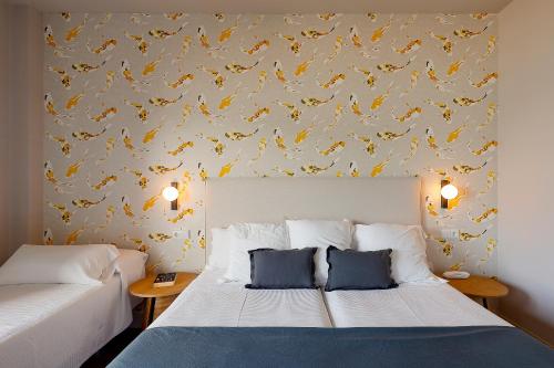 a bedroom with two beds and a wallpaper with yellow birds at Hotel Ribadesella Playa in Ribadesella
