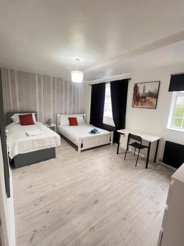 a bedroom with two beds and a desk and a table at London E2 Rooms in London