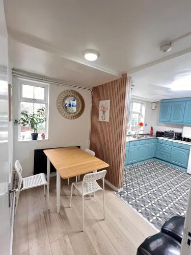 a dining room with a wooden table and a kitchen at London E2 Rooms in London