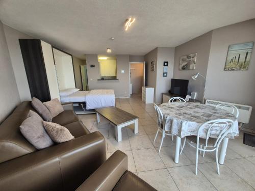a living room with a couch and a table at Large beachstudio seaview Blankenberge near Brugge in Blankenberge