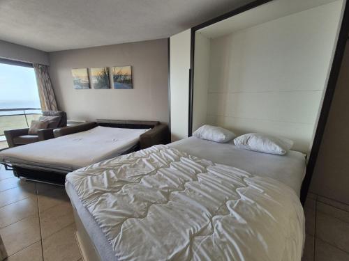 a hotel room with two beds and a chair at Large beachstudio seaview Blankenberge near Brugge in Blankenberge