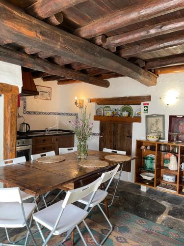 a kitchen with a wooden table and white chairs at Casa do Olho d'Água in Portalegre