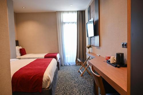 a hotel room with two beds and a desk at Landmark Hotel in Batumi