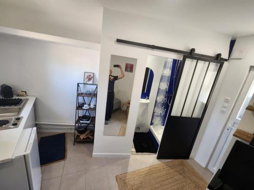 a woman standing in front of a mirror in a kitchen at Studio dans une tour mythique à port grimaud in Grimaud