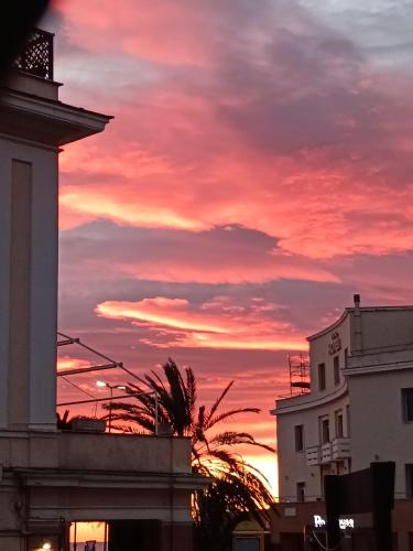 a sunset with a building and a palm tree at B&B Lido Liberty in Lido di Ostia