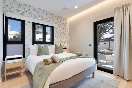 a bedroom with a large white bed and windows at Las Dunas de Santa Catalina Boutique House in Las Palmas de Gran Canaria