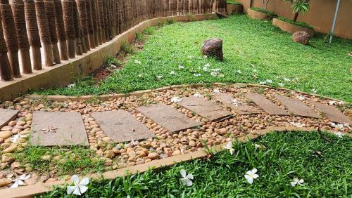 a garden with rocks and flowers in the grass at Cocoon Earth Home - Pool Villa Kovalam in Kovalam