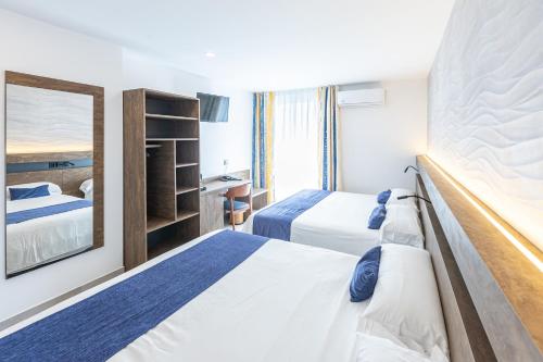 a hotel room with two beds and a mirror at Hotel Internacional in Calella