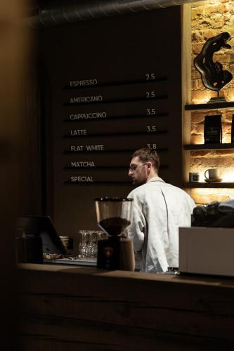 a man standing behind a counter with a blender at Hotel Reja, a Member of Design Hotels in Klaipėda
