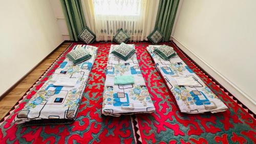a bedroom with three beds on a red carpet at Oroz Guest House in Jangy-Talap