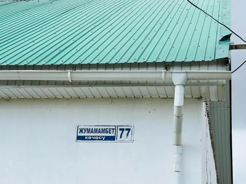 a street sign on a building with a green roof at Oroz Guest House in Jangy-Talap