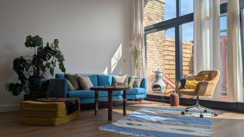 a living room with a blue couch and a chair at Tranquil & Bright by The Canal in London