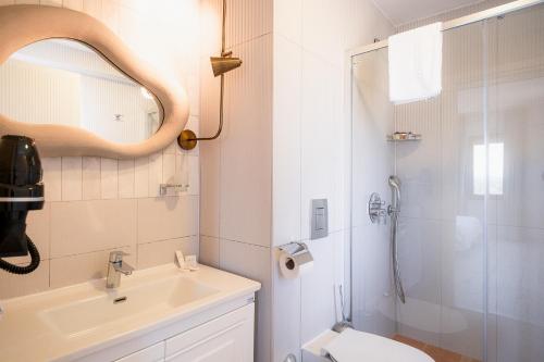 a bathroom with a sink and a shower with a mirror at Dione Bozcaada in Bozcaada