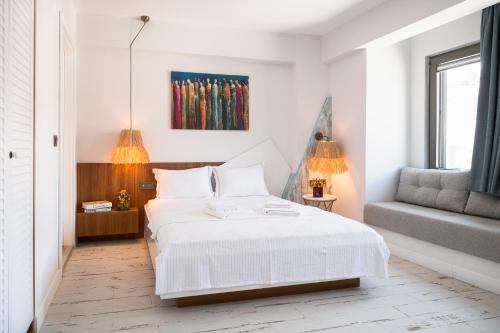 a white bedroom with a bed and a chair at Dione Bozcaada in Bozcaada