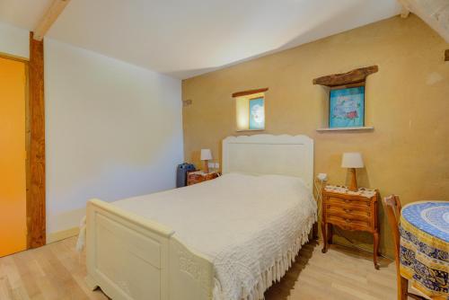 a bedroom with a large white bed and a table at Au fournil de L'essart in Boisgervilly