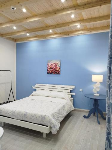 a bedroom with a bed and a blue wall at Il Cortile Fiorito in Trapani