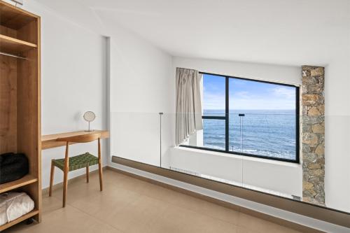 a bedroom with a window with a view of the ocean at Evelmare Beachfront Apartments in Koutsourás