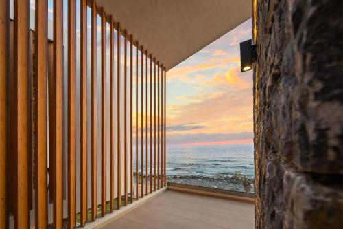 an ocean view from a room with a large window at Evelmare Beachfront Apartments in Koutsourás