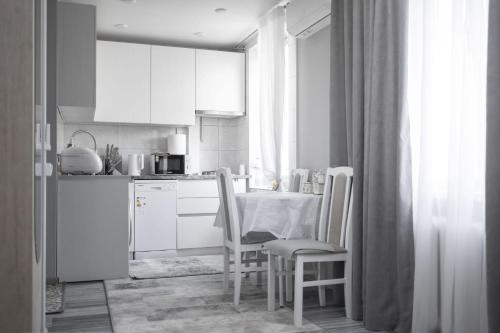 a kitchen with white cabinets and a table and chairs at Stylish Cozy Apartment, Near Chisinau Center in Chişinău