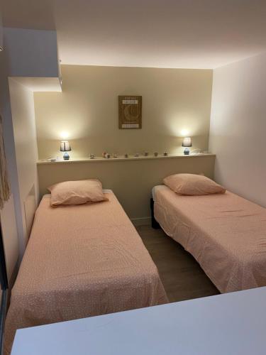 - 2 lits dans une chambre avec 2 lampes sur le mur dans l'établissement Corse du Sud Villa les pieds dans l'eau !, à Zonza