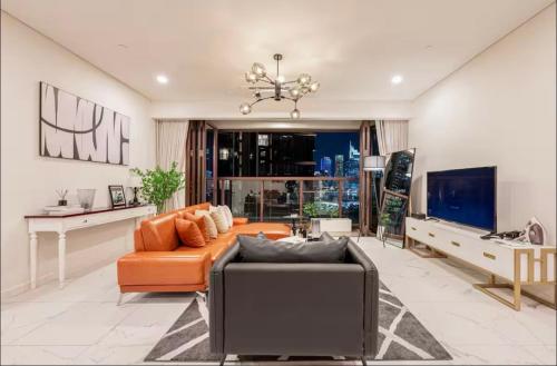 a living room with an orange couch and a tv at THE METROPOLE Apartment Complex OPERA-GALLERIA-CREST in Ho Chi Minh City