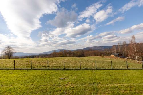 a field of green grass with a fence at Henry Domki - prywatna sauna i jacuzzi in Żywiec