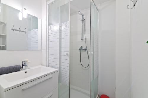 une salle de bain blanche avec une douche et un lavabo dans l'établissement Heart of Paris - Studio - 2P - Invalides Free Netflix, à Paris